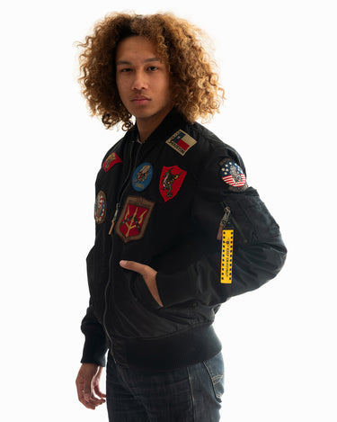Front view of a man with curly hair modeling the black Top Gun® MA-1 bomber jacket #color_black